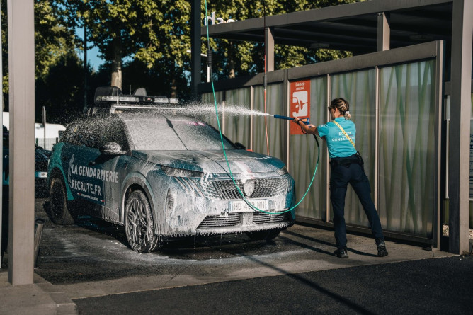 Agrandir l'image Gendarme nettoyant un véhicule de la caravane après course.