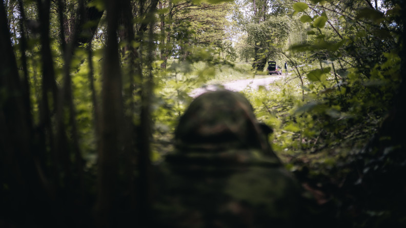 Un &eacute;quipier en ghili observe une voiture.