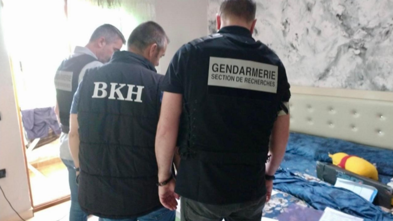 Trois hommes de dos, ceux de gauche et de droite porte une chasuble noire sigl&eacute;e "gendarmerie section de recherches" et celui du milieu un blouson noir sigl&eacute; BKH