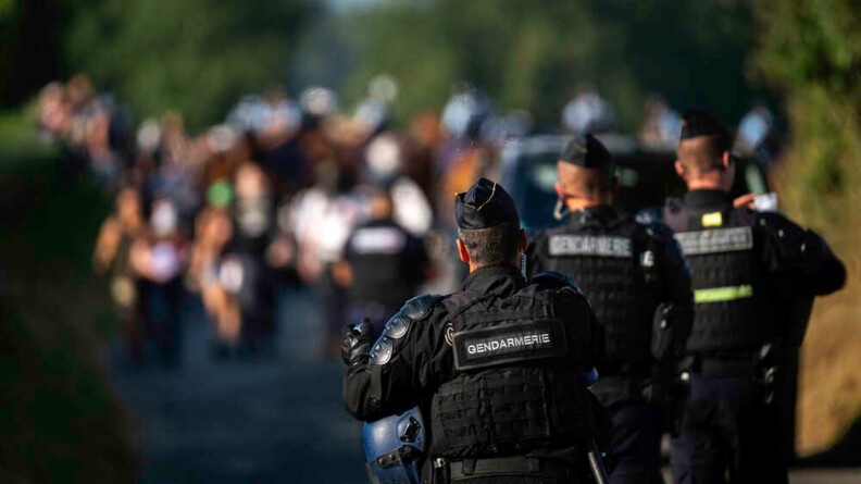 Trois gendarmes mobiles de dos face &agrave; une foule en flou