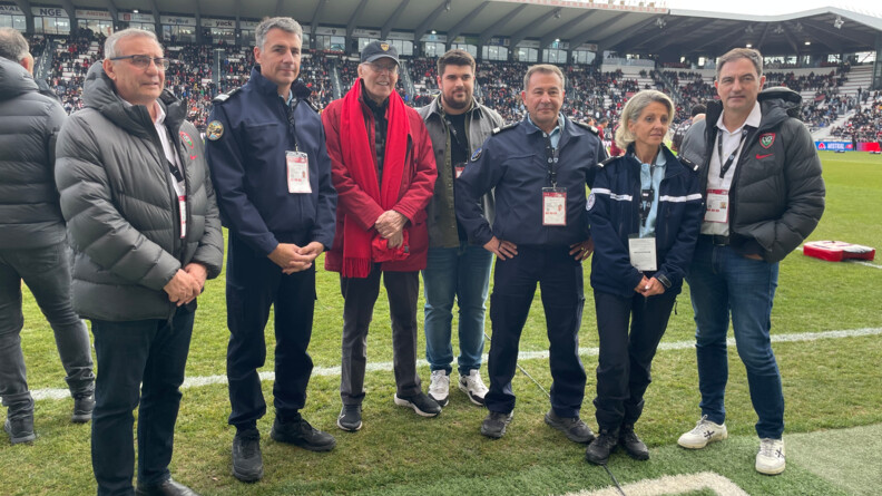 Photo de gendarmes du groupement de gendarmerie départementale du Var, posant debout, aux côtés  d emembres du Rugby Club Toulonnais (RCT) sur la pelouse du Stade Mayol de Toulon. De nombreux spectateurs sont présents dans les gradins.