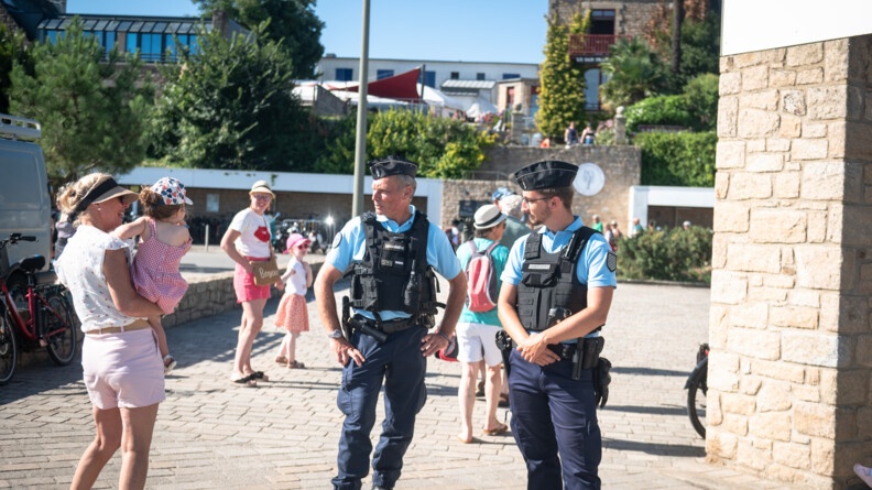 Patrouille de deux gendarmes du poste provisoire de l'Île aux Moines qui échangent avec une dame portant un enfant dans ses bras.