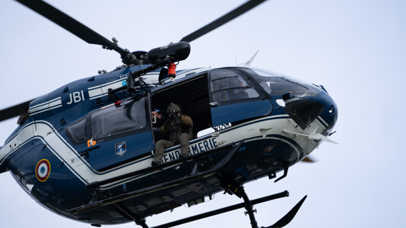Un tireur d'&eacute;lite du GIGN, arme en joue, assis &agrave; la porte d'un h&eacute;licopt&egrave;re des forces a&eacute;riennes de gendarmerie.