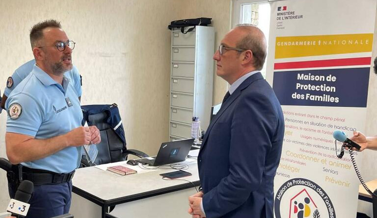 Le ministre Laurent Marcangeli discute avec un gendarme devant un kakemono comportant la mention "Maison de protection des Familles"