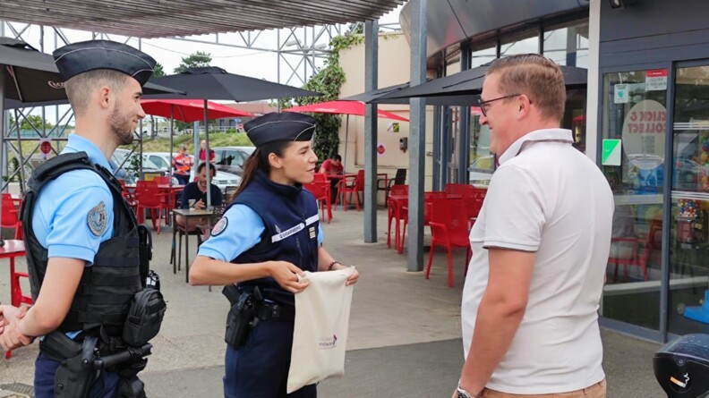 Deux gendarmes donnent des sacs en toile dans le cadre de l'opération de sensibilisation