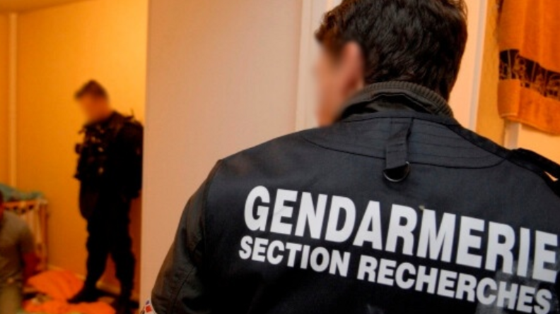 Un enquêteur d'une section de recherches de dos avec le brassard gendarmerie.