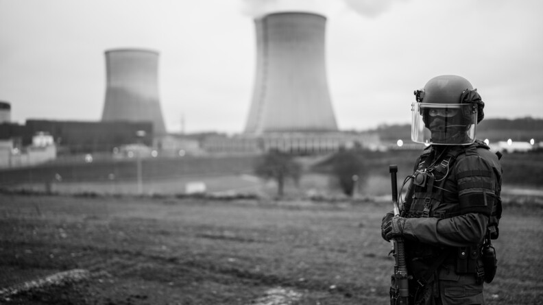 Photo en noir et blanc d'un gendarme qui pose devant la centrale.