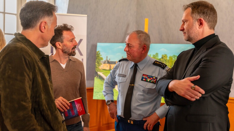 Trois hommes &eacute;changent avec un gendarme dans une salle. Le gendarme est le directeur g&eacute;n&eacute;ral de la gendarmerie nationale. Les trois civils sont des auteurs dont le laur&eacute;at du prix du roman de la gendarmerie.