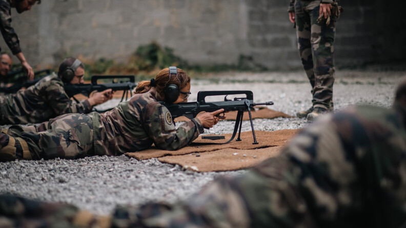 De droite &agrave; gauche, 4 gendarmes en treillis allong&eacute;s au sol, &eacute;quip&eacute;s pour le tir (casque et lunettes), s'entrainent au tir au FAMAS en position allong&eacute;e. La gendarme au centre prend une vis&eacute;e, son FAMAS sur bipieds