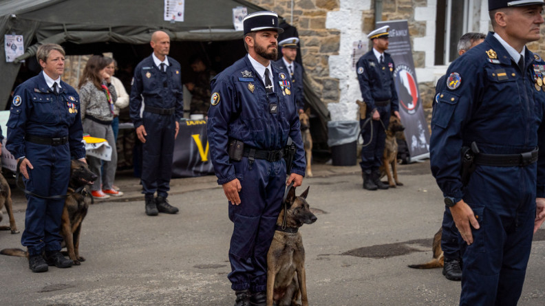 Photo d'un gendarme et de son chein, un berger belge malinois, assis &agrave; ses c&ocirc;t&eacute;s, lors d'une c&eacute;r&eacute;monie officielle