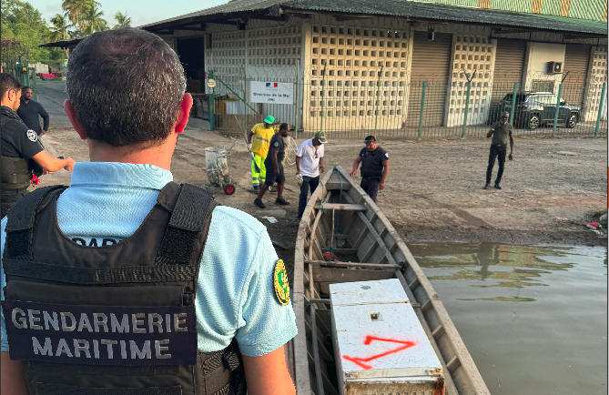 Gendarme surplombant l'embarcation contenant le frigo hors d'usage ramenée à terre.