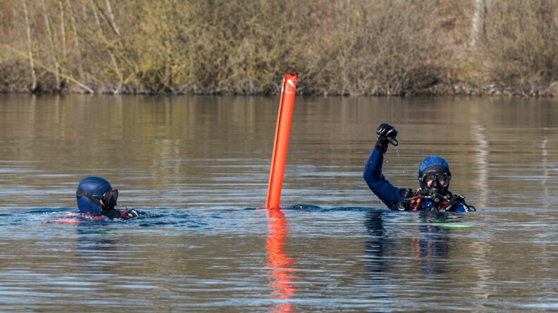Agrandir l'image Deux gendarmes dans l'eau ont localisé le véhicule et l'indique en déployant une balise orange gonflable.