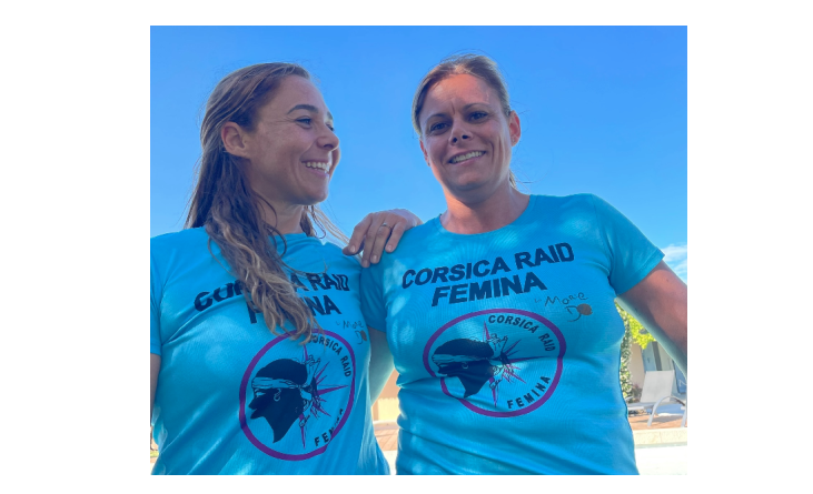 Agrandir l'image Deux femmes d'une quarantaine d'années, souriantes, posent côte à côte, vêtues du même t-shirt bleu portant l'inscription CORSICA RAID FEMINA. l'une d'elle pose sa main sur l'épaule de la seconde femme, regardant dans sa direction.