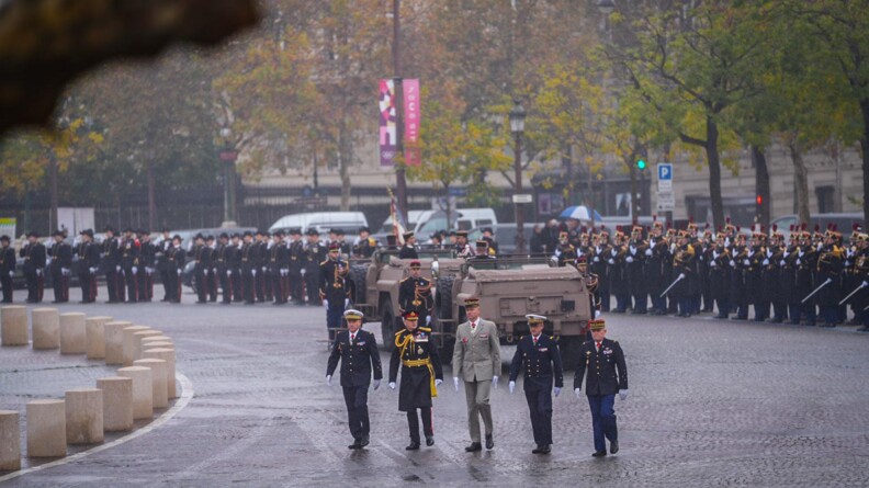 Agrandir l'image 5 autorités militaires marchent dans un rond point devant une command car et les troupes au fond