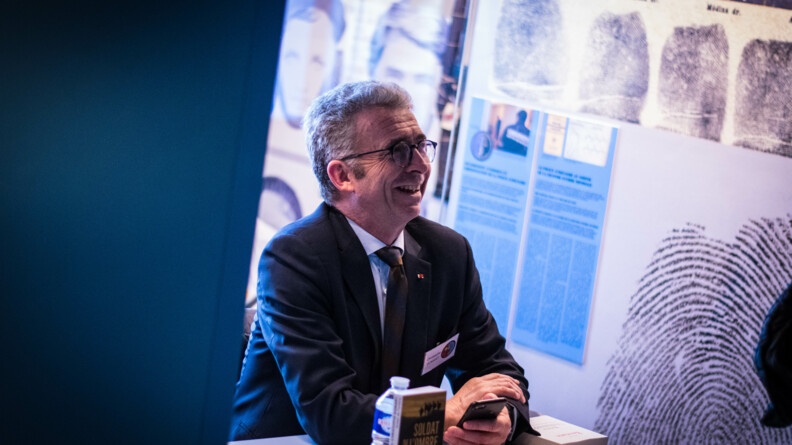 Le général de corps d'armée (2S) Christophe Gomart, ancien chef du commandement des opérations spéciales et de la direction du renseignement militaire, présente son livre, assis à un bureau, au salon littéraire de l'EOGN, samedi 1er avril.