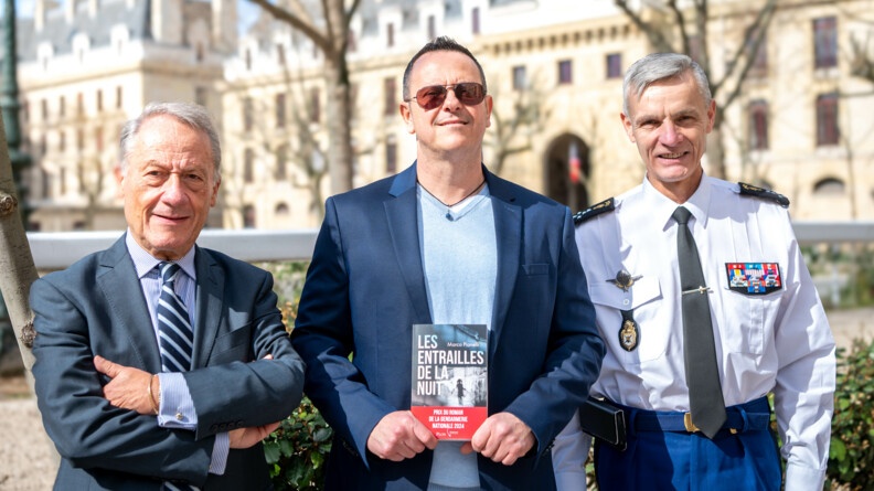 L'IGGN, l'auteur Marco Pianelli et le pr&eacute;sident des &eacute;ditions PLON prennent une photo tous les trois, avec le quartier des C&eacute;lestins en arri&egrave;re plan, il fait beau et l'auteur tient son livre en main.