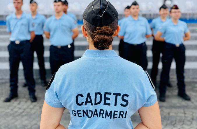 Agrandir l'image Une jeune femme, cadet de la gendarmerie, se tient de dos, mains croisées dans le dos, face à d'autres gendarmes.