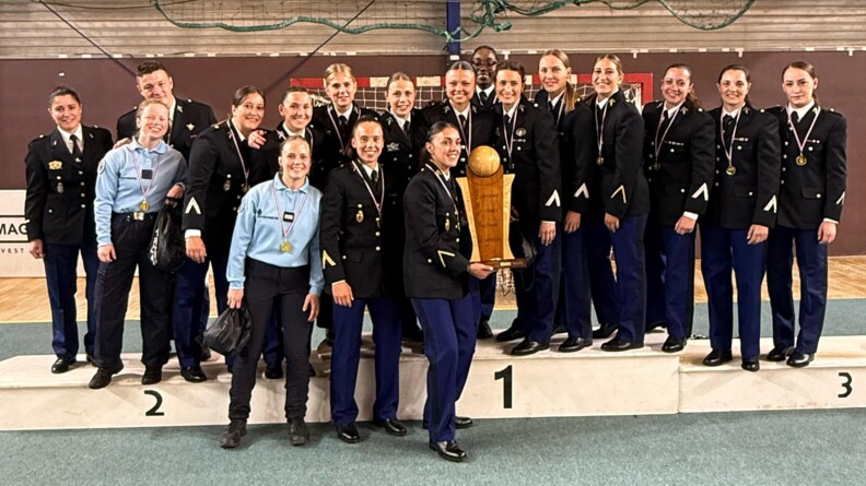 Agrandir l'image Une quinzaine de gendarmes féminins, dont la majorité est en vareuse et les autres en tenue d'intervention, posent en groupe dans un gymnase, sur et devant un podium. Au milieu, une gendarme brandit un trophée. Toutes ont une médaille autour du cou.