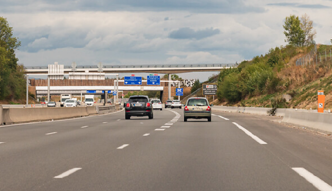 Des voitures, filmées par l'arrière, circulent sur une autoroute. Le trafic est fluide. La cène se déroule de jour.