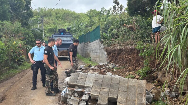 Agrandir l'image Des gendarmes participent au déblaiement d'une route partiellement barrée par des briques, après le passage du cyclone Garance à La Réunion.