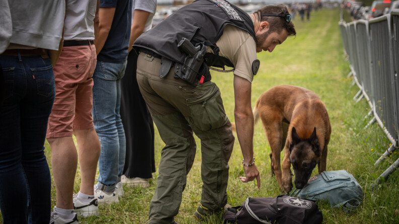 Agrandir l'image Une équipe cynophile vérifie les sacs des spectateurs autour du château de Chambord. Le gendarme pointe un sac pour que le chien le renifle.