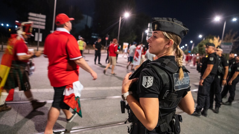 Au premier plan, une gendarme mobile f&eacute;minin observe le flux de supporters gallois qui passent devant elle. &Agrave; droite, d'autres gendarmes jalonnent le parcours.