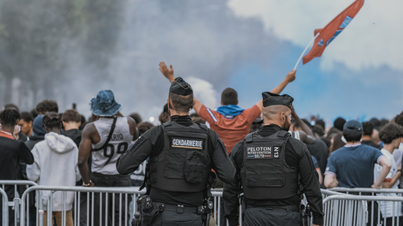 Photo de deux gendarmes, de dos, lors des festivités à l'occasion de la victoire du PSG lors de la Ligue des Champions 2025