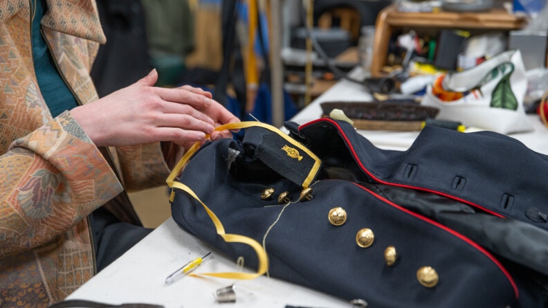 Plan rapproch&eacute; des mains de la couturi&egrave;re cousant une veste de Garde.