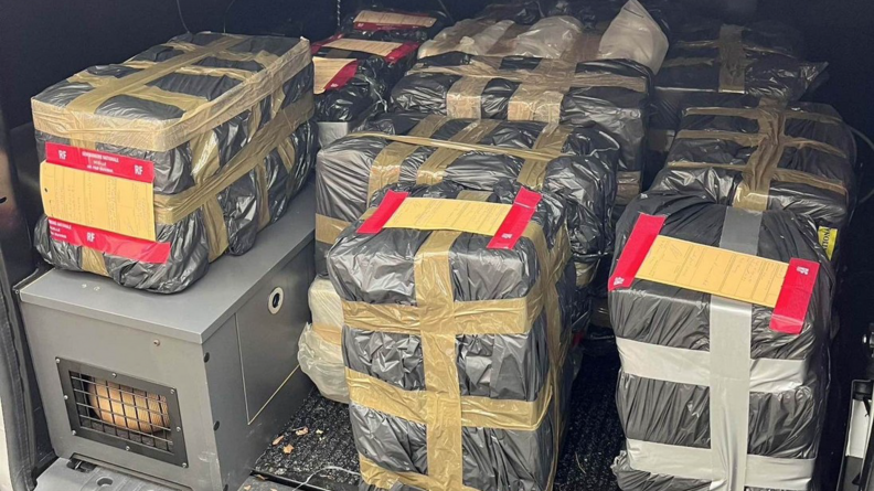 Plusieurs gros paquets emball&eacute;s dans du plastique noir entass&eacute;s &agrave; l'arri&egrave;re d'un v&eacute;hicule utilitaire.