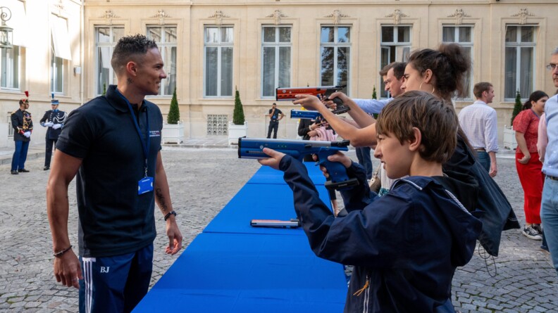 Le pentathlète moderne Christopher Patte à gauche, face à plusieurs tireurs sur le stand de tir, à l'hôtel Beauvau.