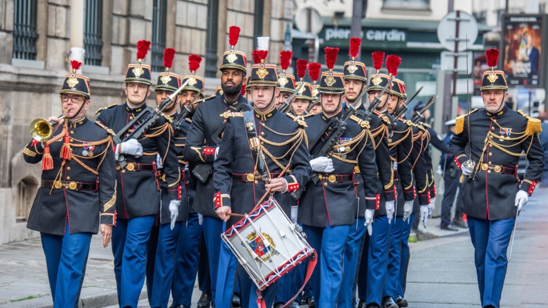 Militaires de la Garde républicaine avançant dans la rue lors de la grande relève. Le premier tient un tambour