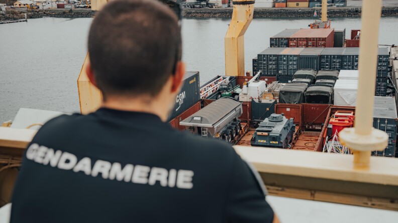 Arrivée de fret au port de Mayotte avec un gendarme de dos qui regarde