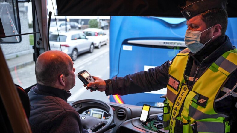 Agrandir l'image Un gendarme avec une chasuble jaune fluo, fait souffler un conducteur de bus assit derrière son volant.