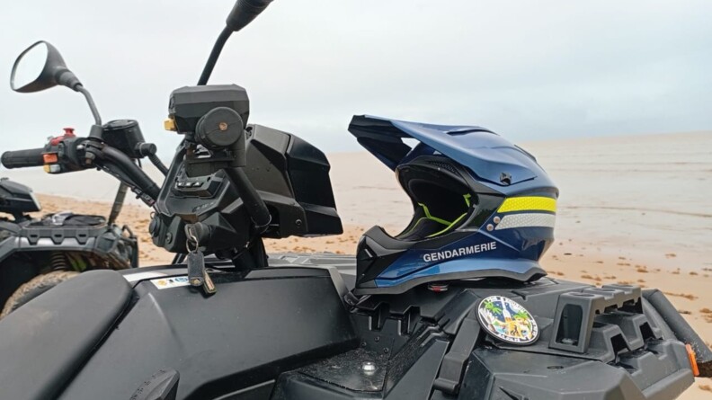 Agrandir l'image Photo d'un quad, garé sur une plage, sur lequel est posé un casque bleu portant l'inscription "Gendarmerie".