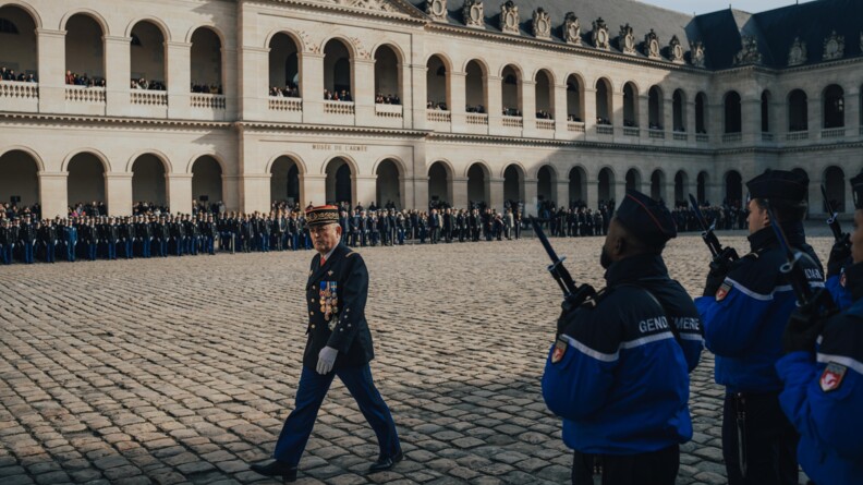 Le directeur général de la gendarmerie marche devant ses troupes dans la cour pavée des invalides