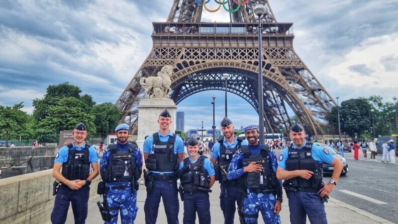 Cinq élèves-gendarmes posent avec deux policiers étrangers au pied de la Tour Eiffel.