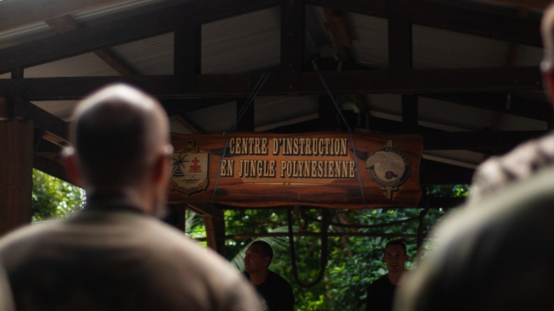 Panneau du centre d'instruction en jungle polyn&eacute;sienne avec deux militaires au premier plan de dos