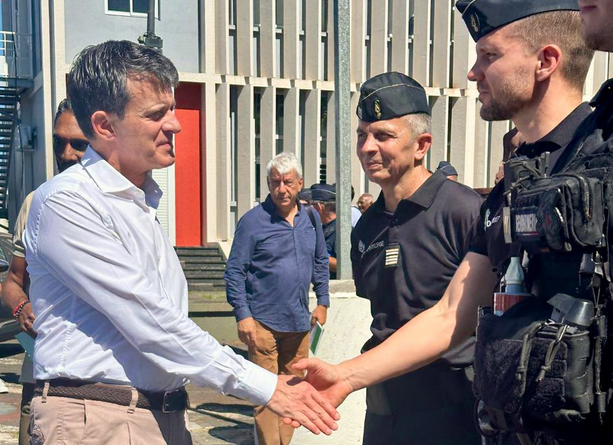 Agrandir l'image Le ministre des Outre-mer, Emmanuel Valls, en visite sur l'île de La Réunion, après le passage du cyclone Garance, serre la main d'un gendarme. A leurs côtés se tient un second gendarme.
