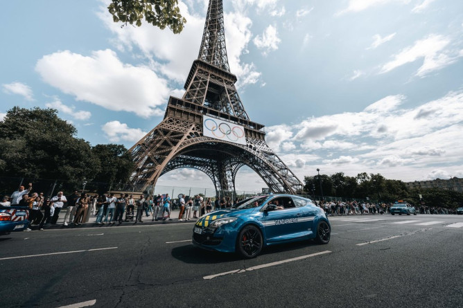 Agrandir l'image Une voiture de la gendarmerie passe devant la Tour Eiffel, sur laquelle sont aposés les anneaux olympiques