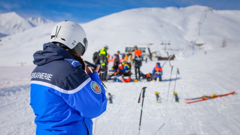 Gendarme au t&eacute;l&eacute;phone avec l'accident de ski en fond.