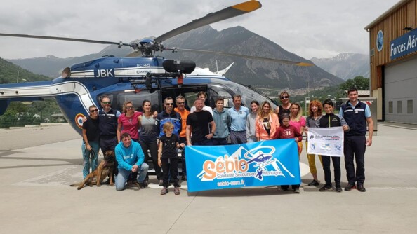 Les participants à cette nouvelle édition de Rêves de Cimes, devant un hélicoptère de la gendarmerie. En fond, on observe les montagnes.