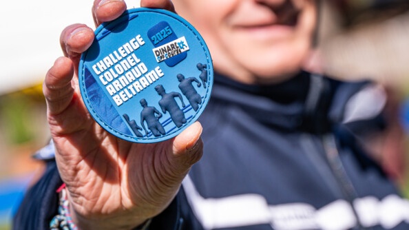 Photo d'un écusson portant la mention "Challenge colonel Arnaud Beltrame 2025" qu'un gendarme tient dans sa main, face à l'objectif.