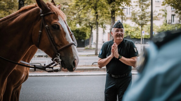 Le directeur général de la gendarmerie nationale échange avec un gendarme que l'on aperçoit de dos. A la gauche de la photo se trouve la tête d'un cheval.