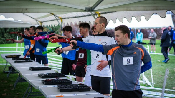 Photo d'extérieur montrant les élèves de plusieurs écoles de la défense, en ligne derrière des tables entrain de tirer lors d'une des épreuves du tournoi sportif des grandes écoles de la Défense