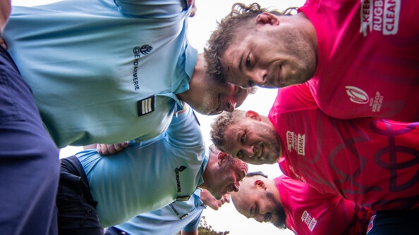 Vus en contre plongée, trois gendarmes à gauche et trois rugbymen à droite, en première ligne de rugby, prêts