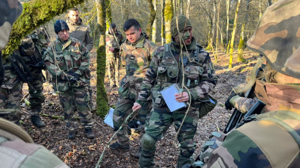 10 gendarmes dans la fo&ecirc;t en cercle. Un d'entre eux tiens un b&acirc;ton et leur donne des directives &agrave; suivre gr&acirc;ce &agrave; un schema sur le sol. Ce briefing est cont&ocirc;l&eacute; par le GCA.
