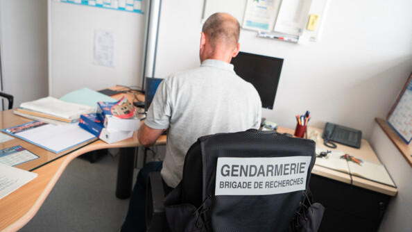 Un enquêteur de brigade de recherches de dos à son bureau