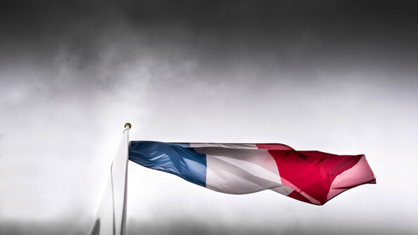 Drapeau en berne dans un ciel gris orageux.