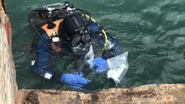 Un technicien en investigations subaquatiques remonte des prélèvements aux abords du silo détruit par l'explosion.