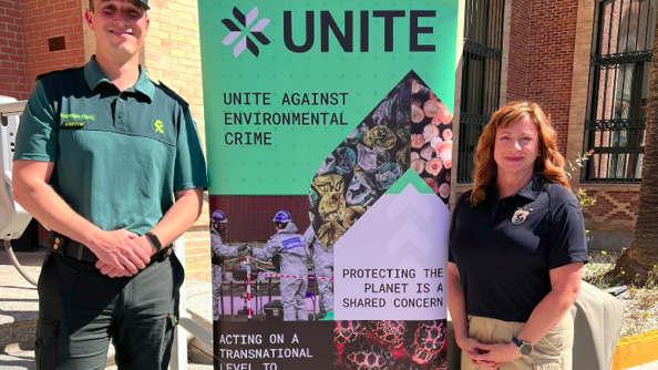 Un personnel de la Guardia civil et une représentante des services de protection de la biodiversité aux Etats-Unis posent devant une affiche promouvant le projet UNITE.